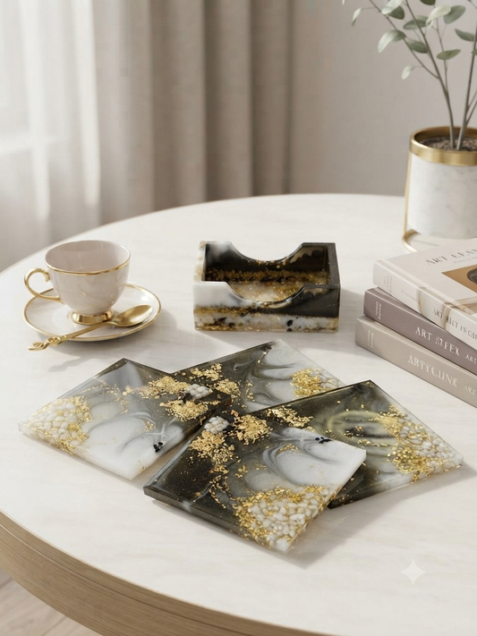 Set of 4 handmade black white and grey marble swirl resin coasters with gold leaf, displayed with matching resin holder on a white marble coffee table with a gold-rimmed tea cup